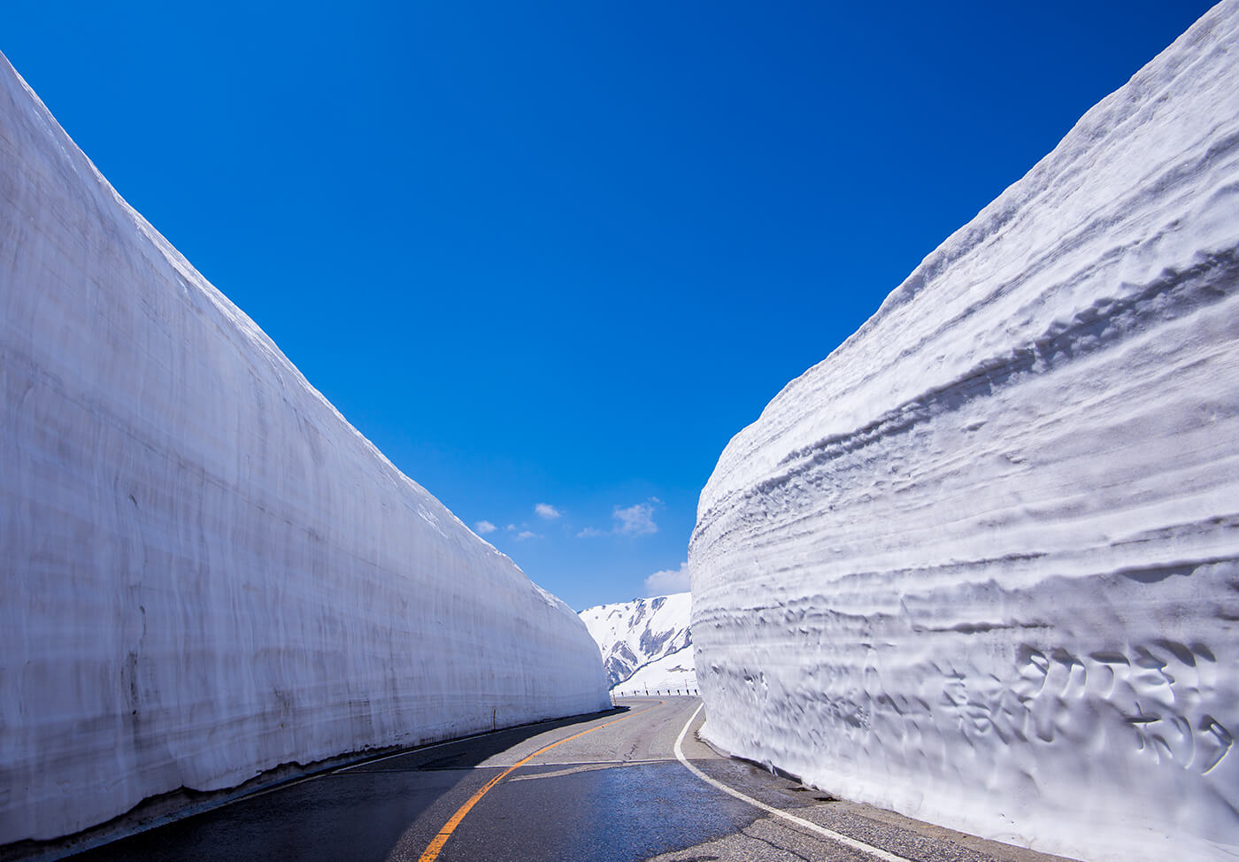 Autobús pasando entre muros de nieve gigantes.