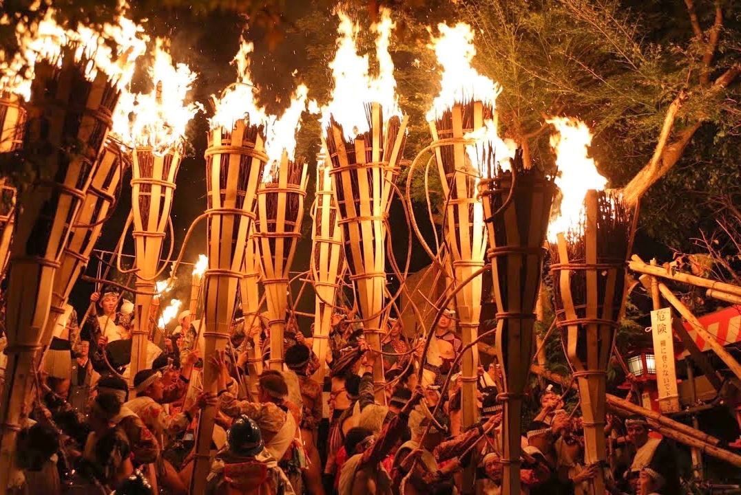 Hombres cargando antorchas de paja ardiendo.