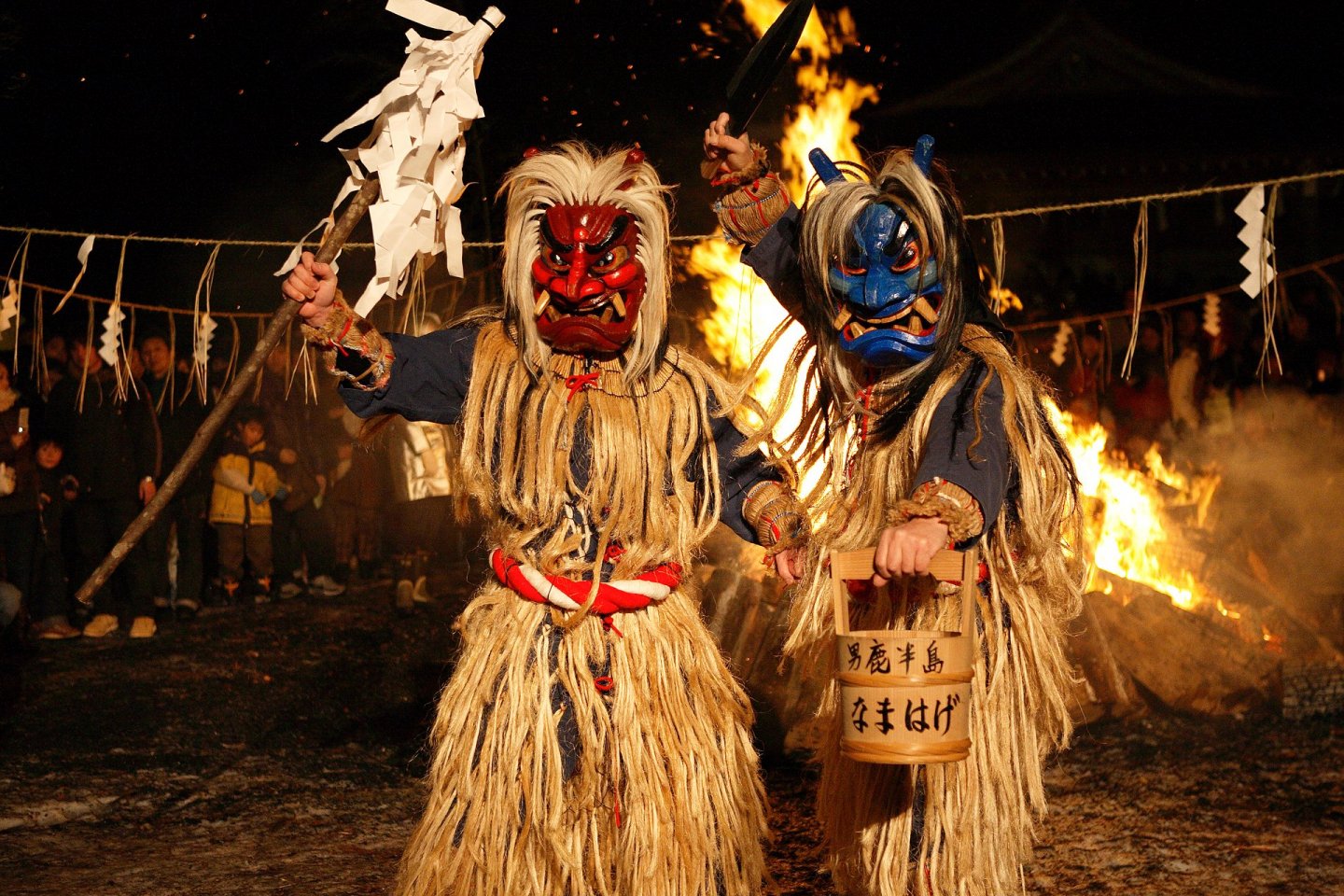 Demonios con paja y máscaras feroces frente a hogueras.