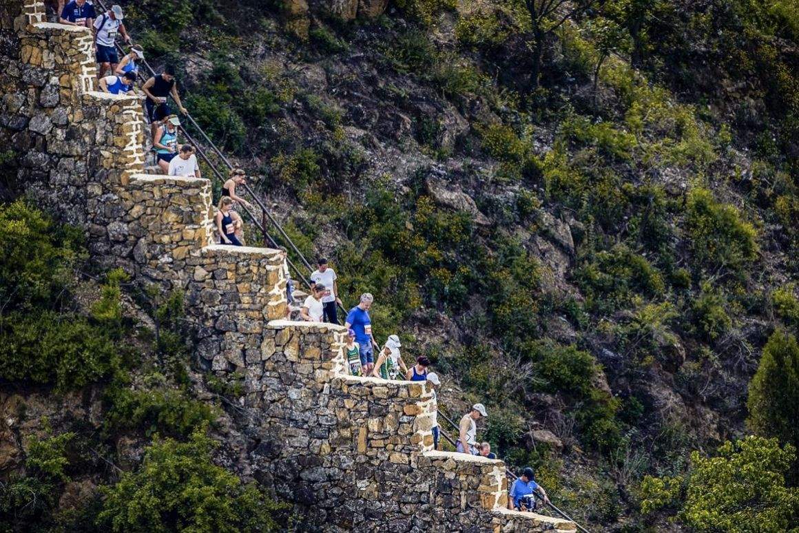 Corredores subiendo escalones de piedra en la muralla.