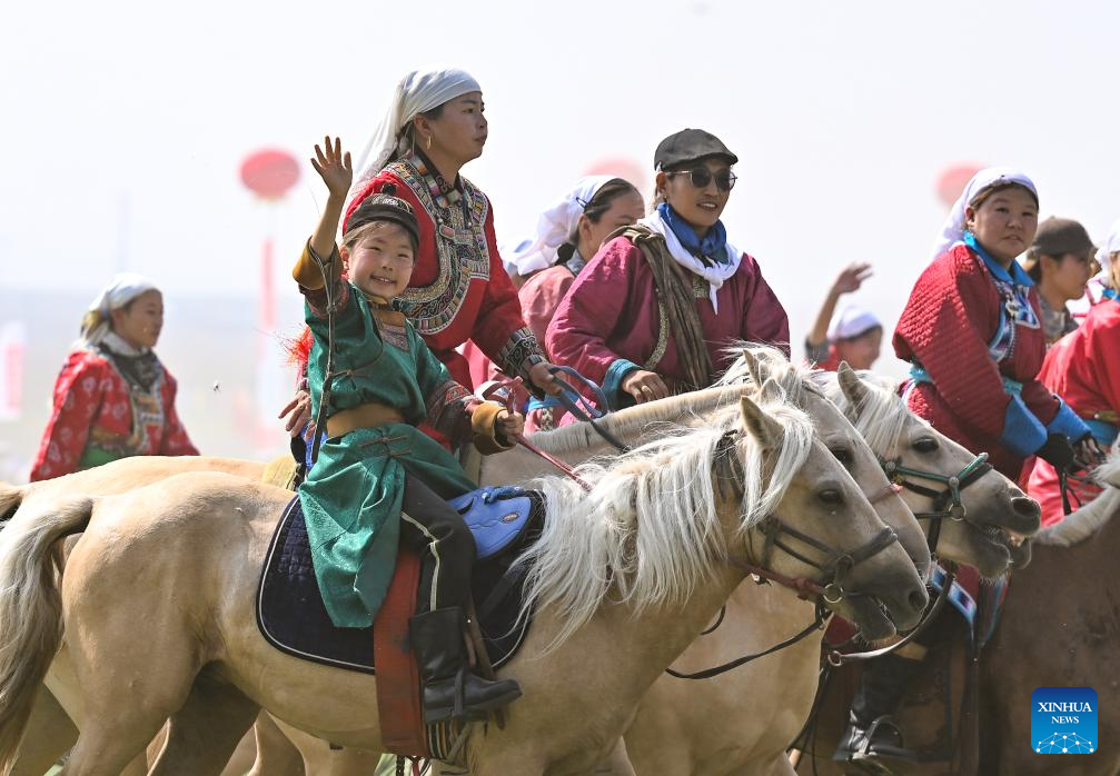 Luchadores mongoles con trajes de cuero en el pasto.