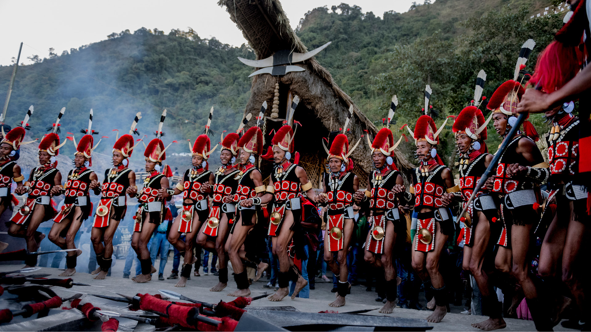 Guerreros tribales con plumas y lanzas bailando.