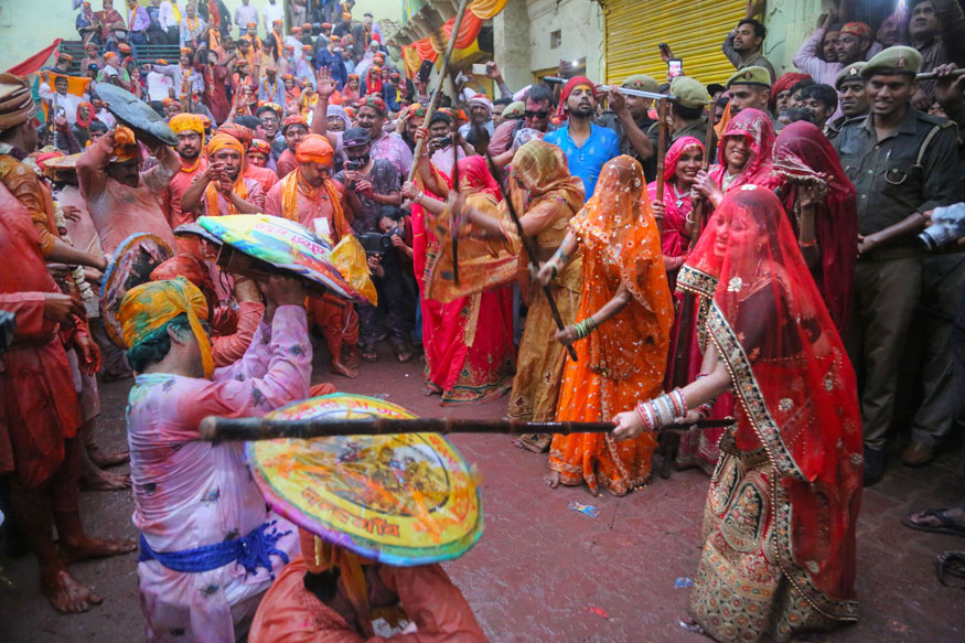 Mujeres con palos y hombres con escudos en Holi.