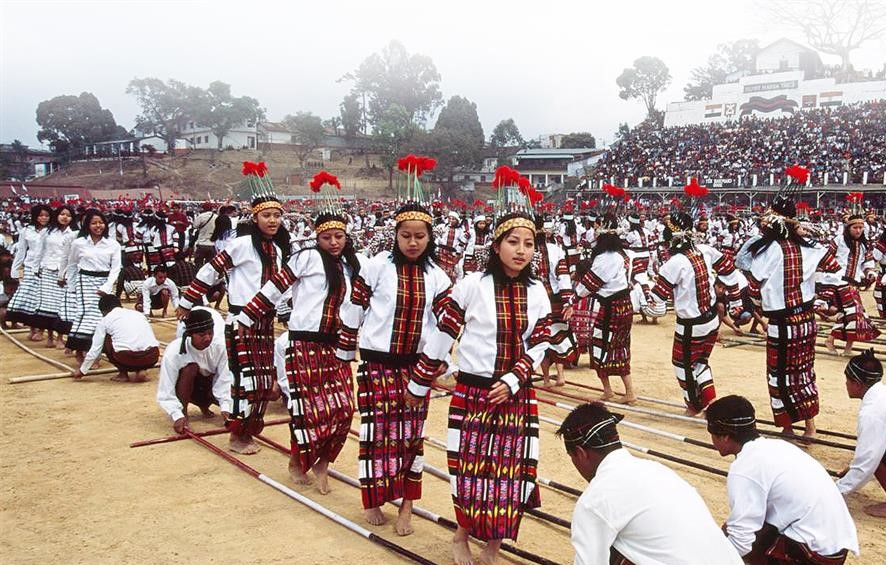 Mujeres bailando entre palos de bambú golpeados.