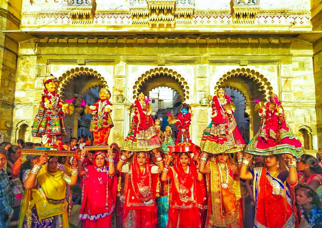 Mujeres con trajes rojos y barcos en el lago de Udaipur.