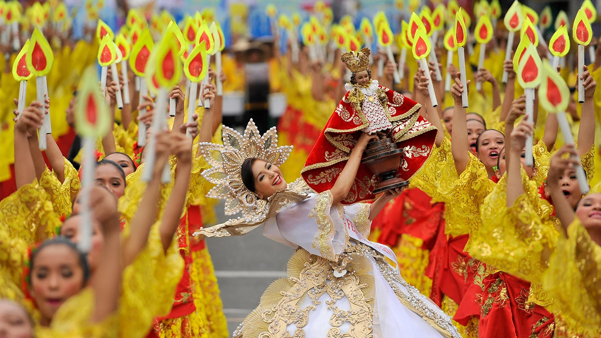 Bailarines con trajes de plumas doradas en la calle.