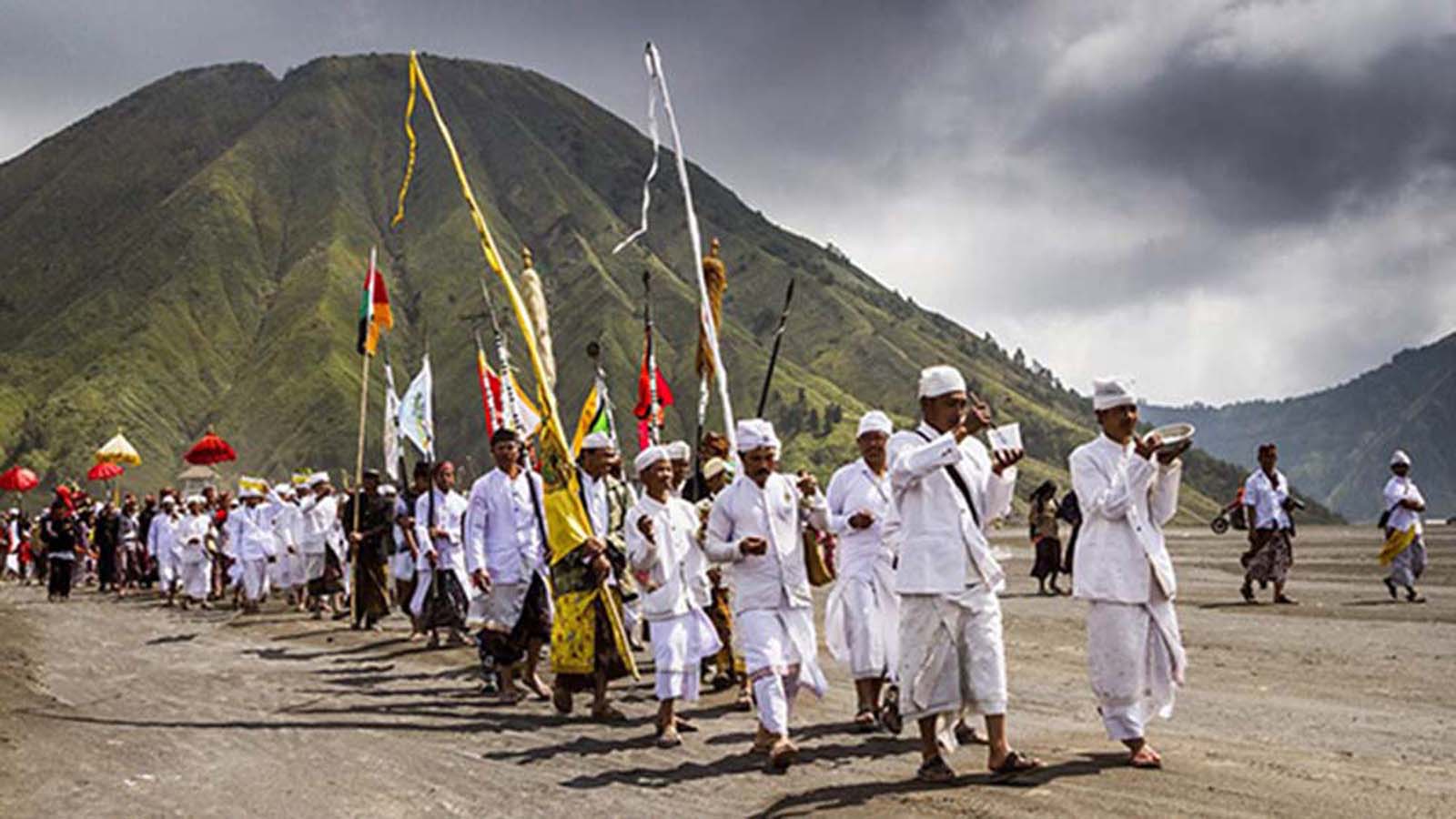 Gente en el borde del cráter del volcán con ofrendas.