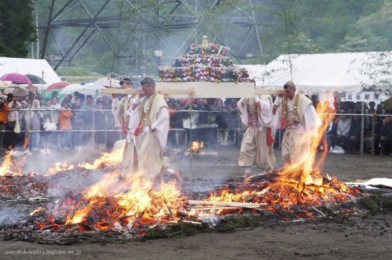 Hombre con traje tradicional caminando sobre piedras calientes.