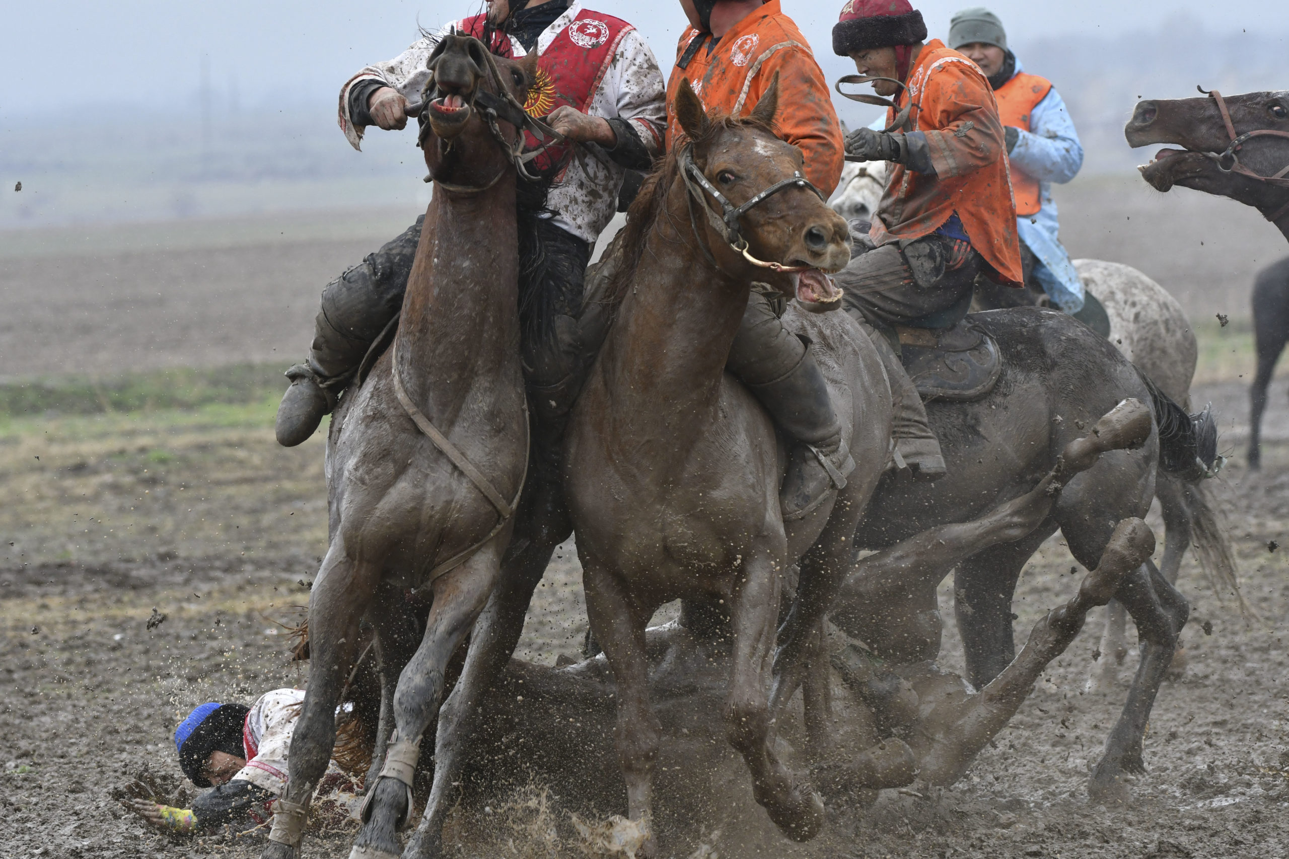 Jinetes luchando en un valle árido rodeado de picos.