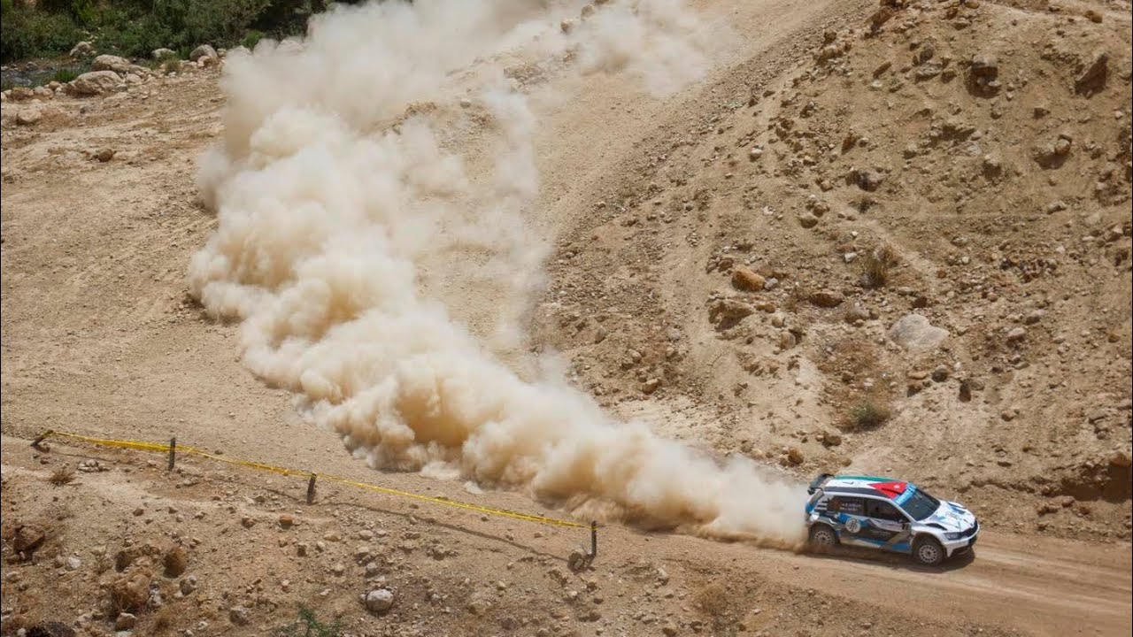 Coche de rally levantando polvo con el Mar Muerto de fondo.