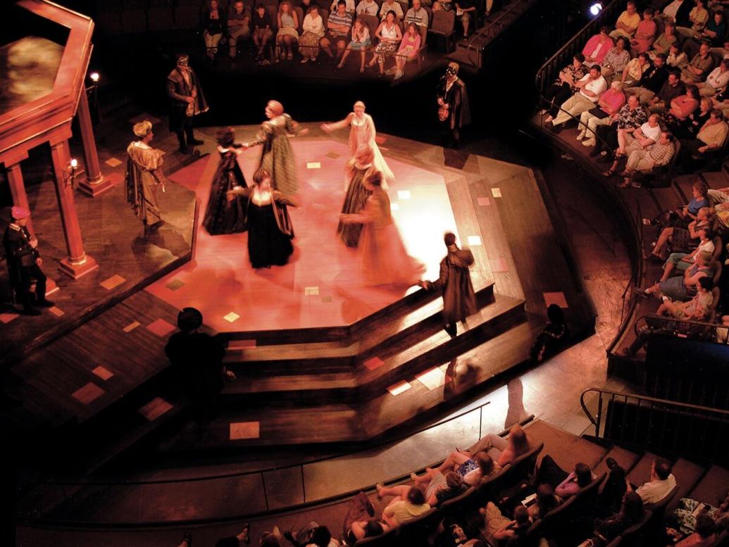Actores con trajes de época en un teatro circular.
