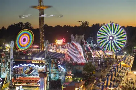 Noria gigante y luces de feria al atardecer.