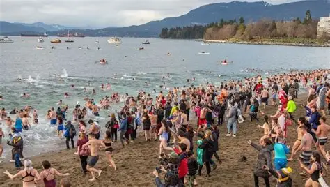 Multitud corriendo hacia el mar frío en invierno.