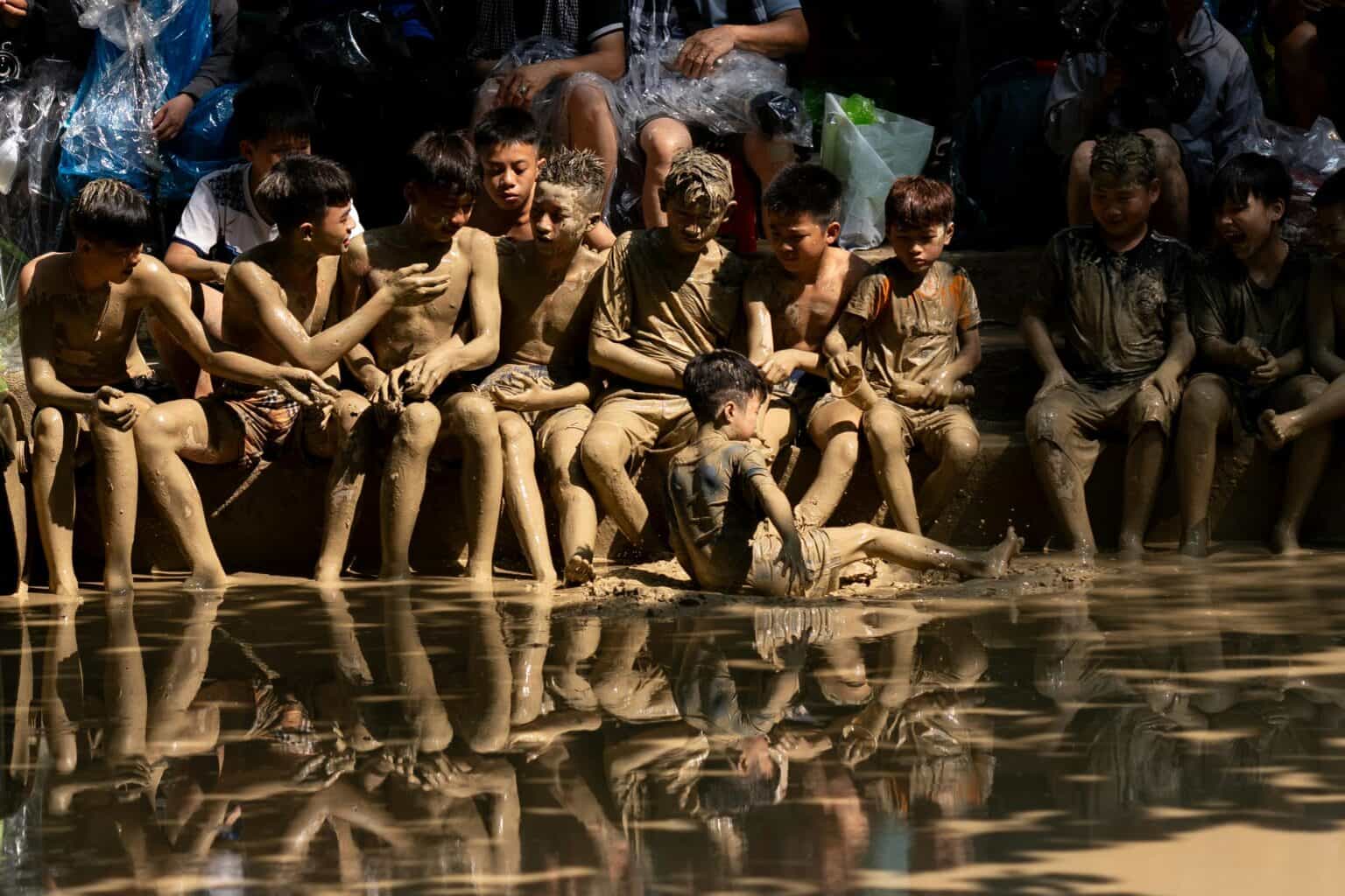 Gente cubierta de barro bailando en un escenario de playa.
