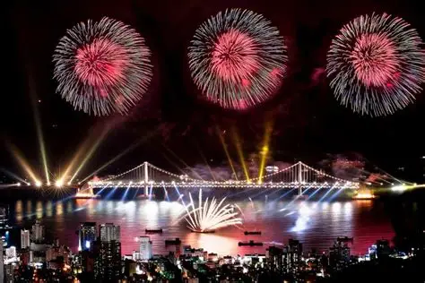 Puente gigante iluminado por explosiones de colores sobre el mar.