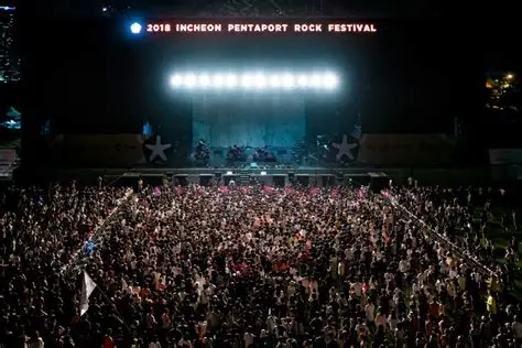Multitud saltando frente a un escenario de rock moderno.