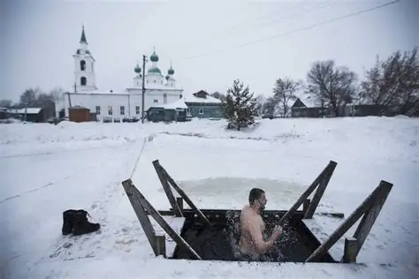 Hombre saliendo de un agujero en el hielo con forma de cruz.