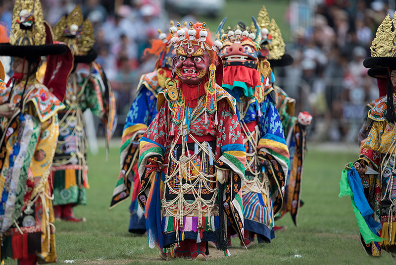 Monjes budistas con máscaras coloridas bailando.