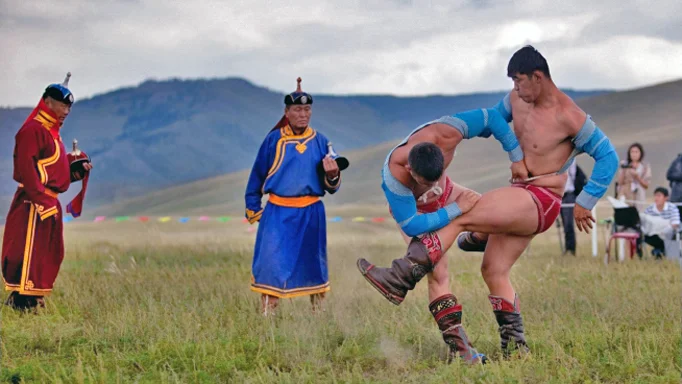 Dos luchadores mongoles agarrados en el césped.