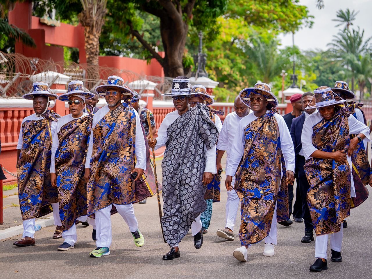 Hombres vestidos de blanco con bastones tradicionales en la calle.