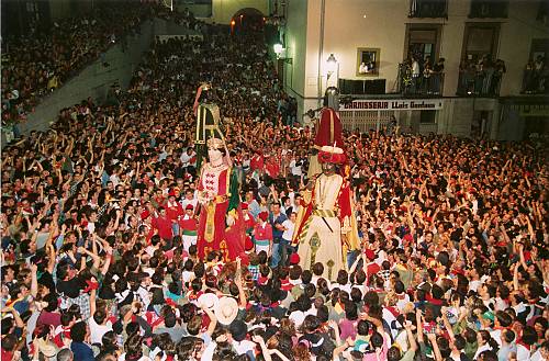 Figuras de demonios cubiertas de hierba y fuego en una plaza.