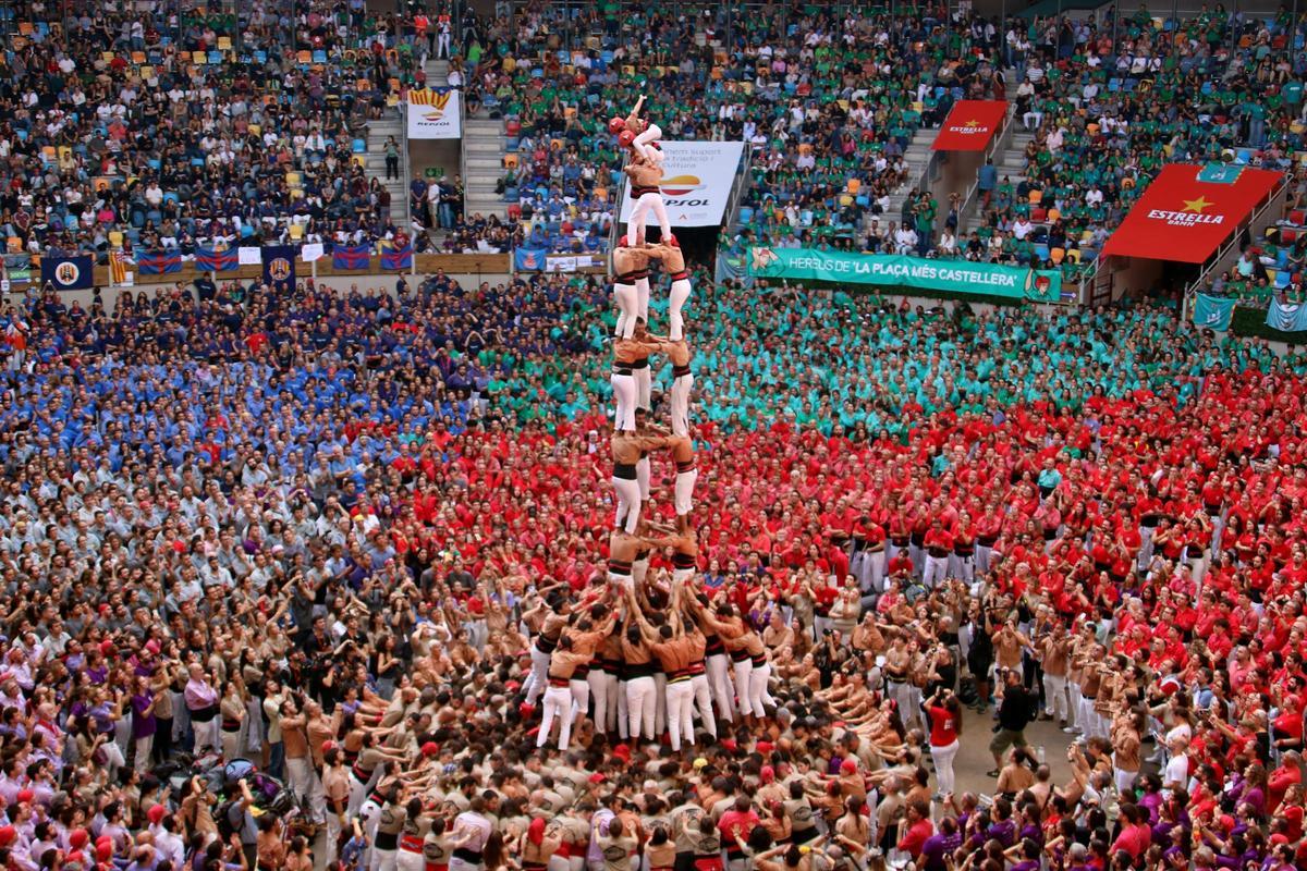 Torre humana gigante en una plaza de toros llena de colores.