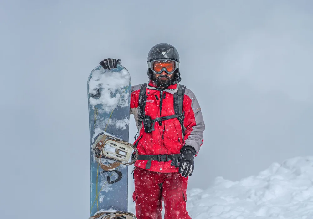 A snowboarder in red gear standing in fresh snow
