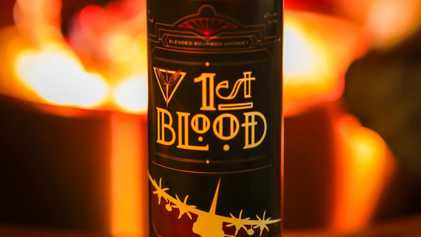 A bottle of 1st Blood bourbon lit by an open fire.