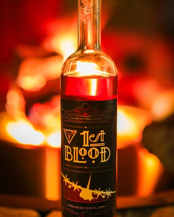 A bottle of 1st Blood lit by an open fire.