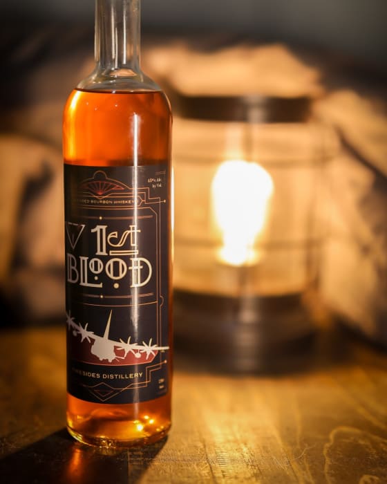 A bottle of 1st Blood beside a lit lantern.