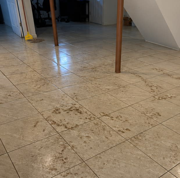 Basement tile floor streaked with sewage debris after a backup, before Restorehaus cleaned it