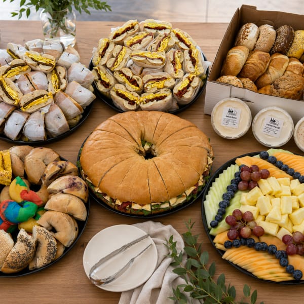 Catering platters of bagels, sandwiches and fresh fruit