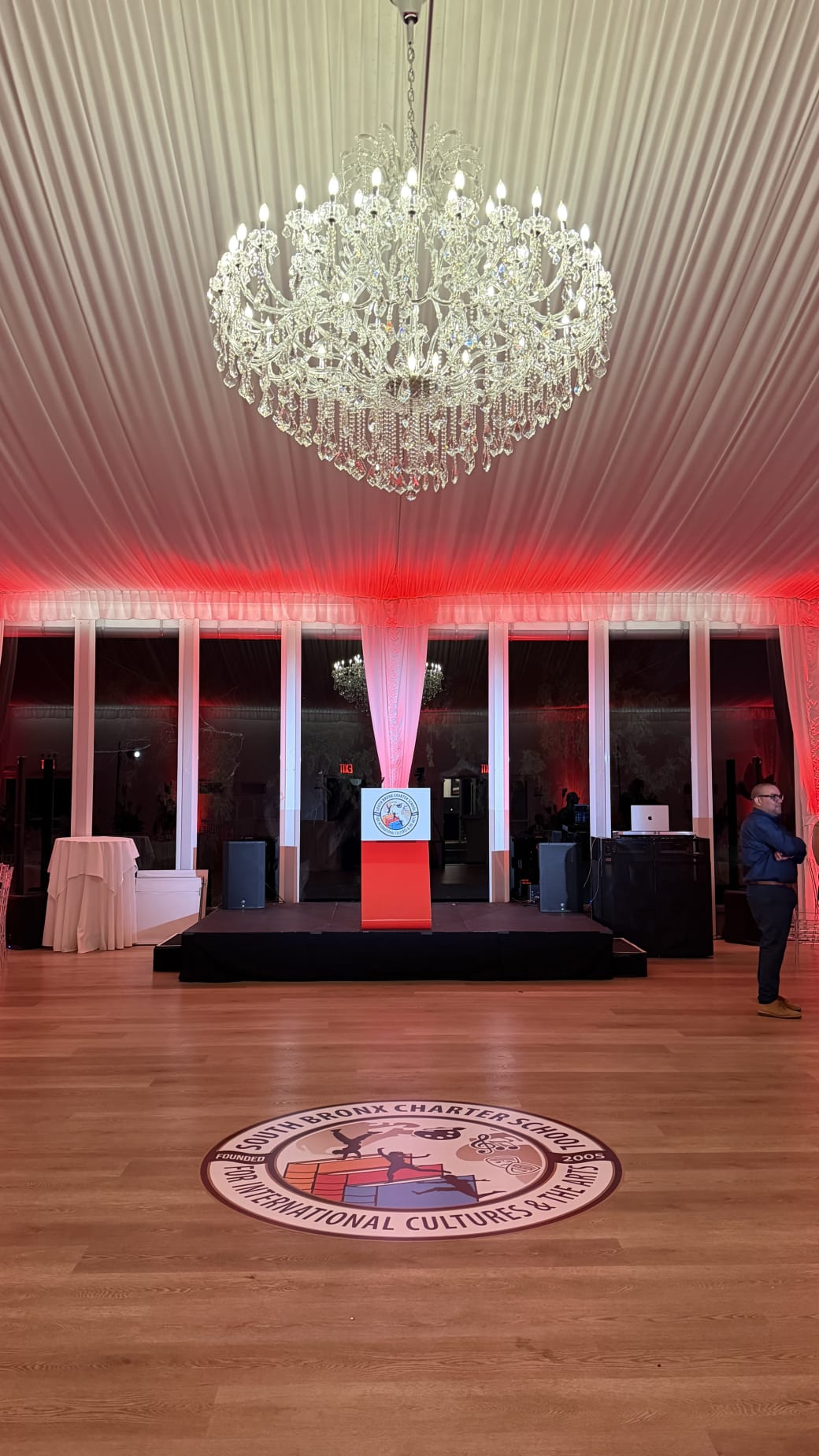 South Bronx Charter School for International Cultures and the Arts gala tent with a branded podium sign and a floor decal of the school seal