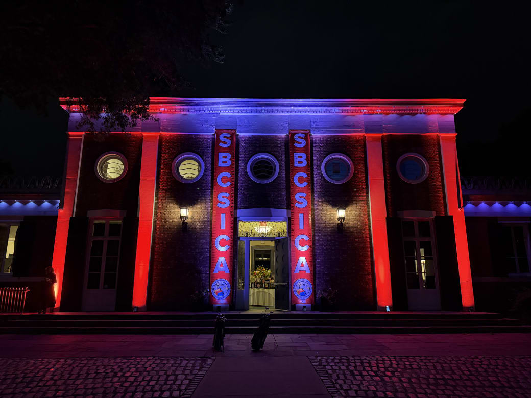 Two tall SBCSICA vertical banners flanking the gala venue entrance at night