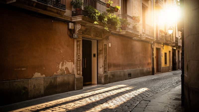 Entrada discreta a un club social de cannabis en una calle adoquinada de Madrid al atardecer