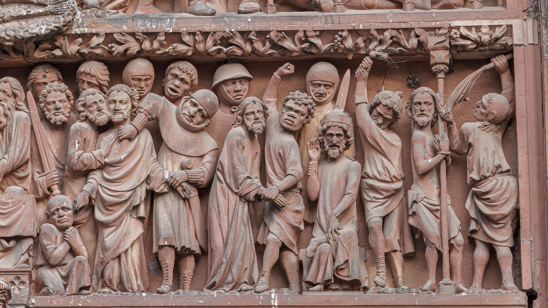 A striking architectural close-up capturing a moment of profound spiritual drama from the Passion narrative on the facade of Strasbourg Cathedral. The high-relief stone carving depicts the resurrection or ascension, centered on a figure draped in beautifully sculpted shroud-like robes, surrounded by witnessing figures filled with awe and reverence. The image highlights the fluid movement of the medieval drapery and the rich, sand-textured grain of the historic pink sandstone.