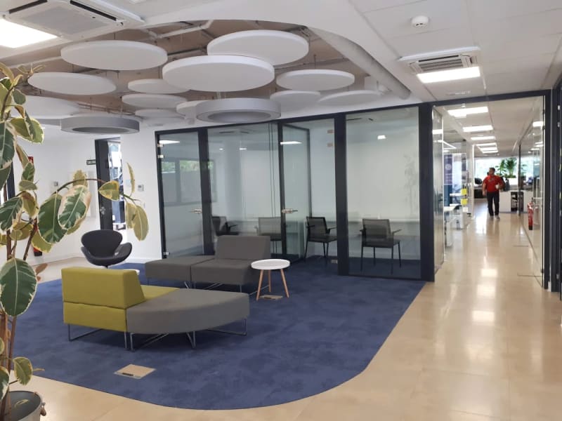 Zona lounge con asientos modulares y alfombra azul en un coworking de Teatinos, Málaga