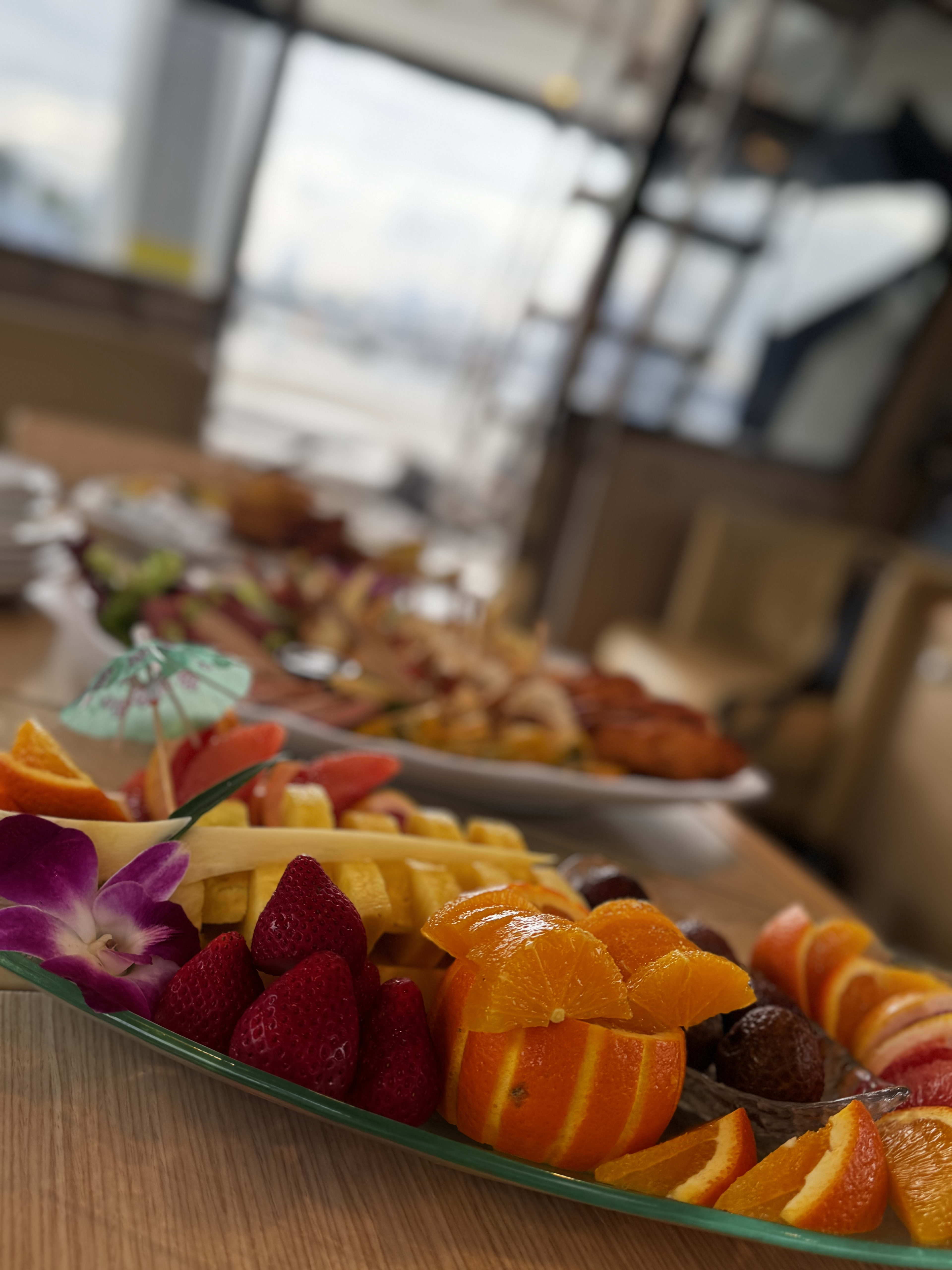 Fruit platter of oranges and strawberries decorated with purple orchids and cocktail umbrellas