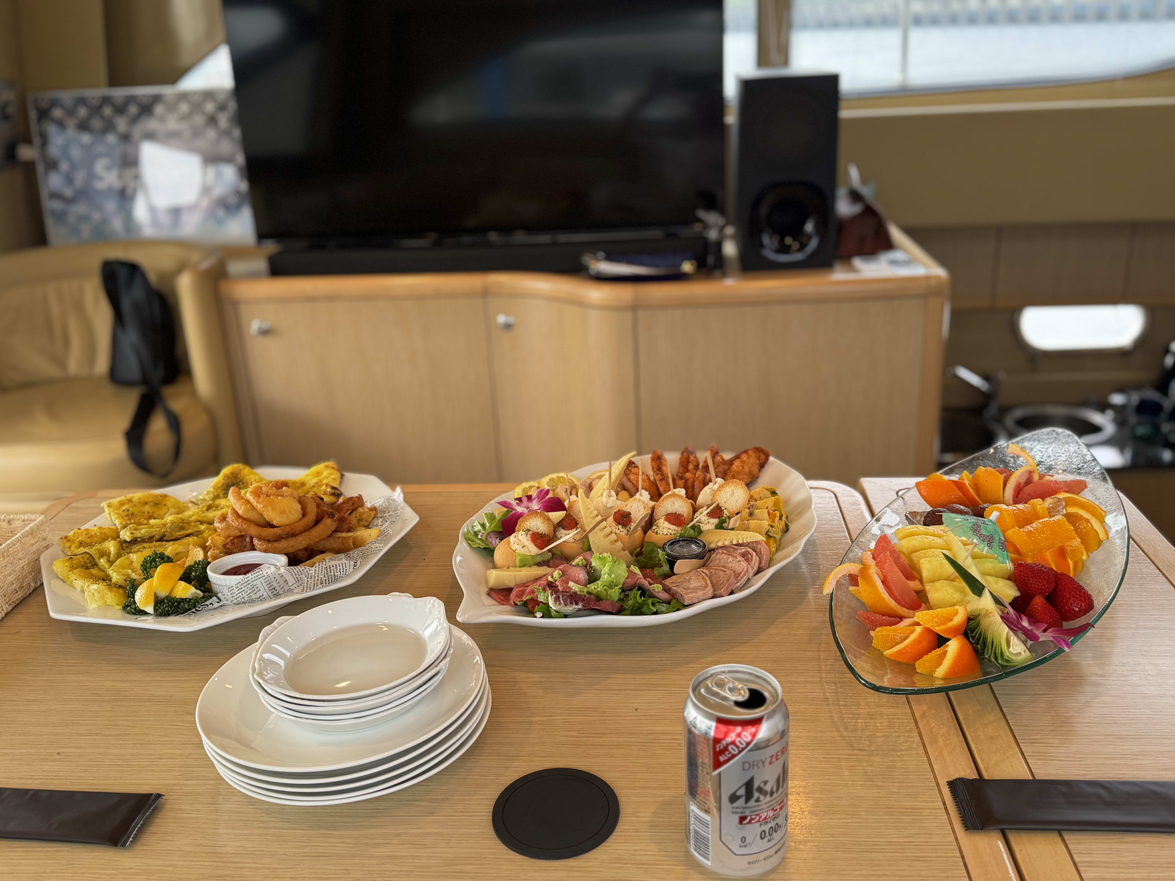 Fried appetizers, charcuterie, a fresh fruit platter and a can of Asahi beer on the yacht's table