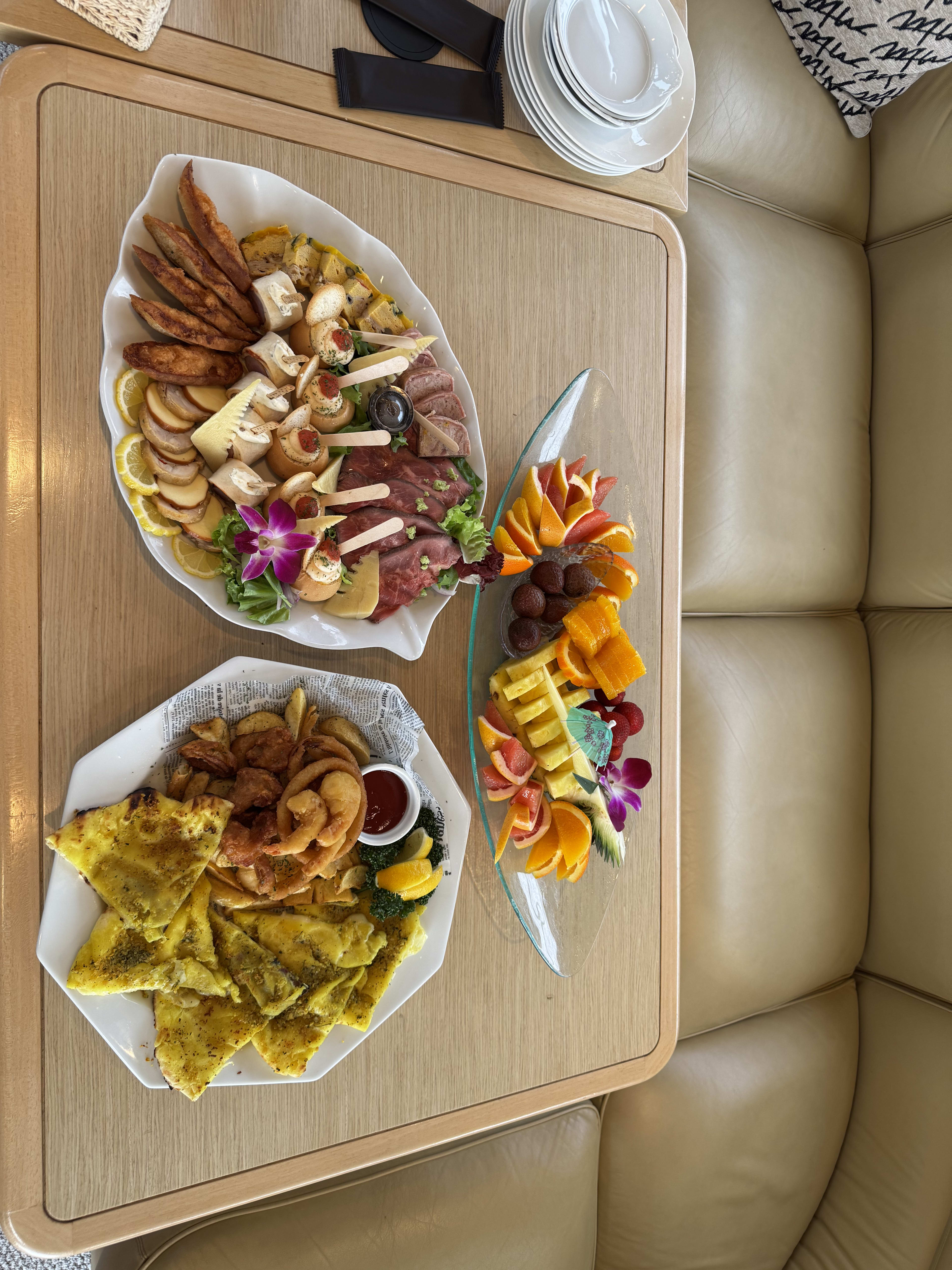Charcuterie board, fruit platter with oranges and flowers, and flatbread with sides on the yacht's table