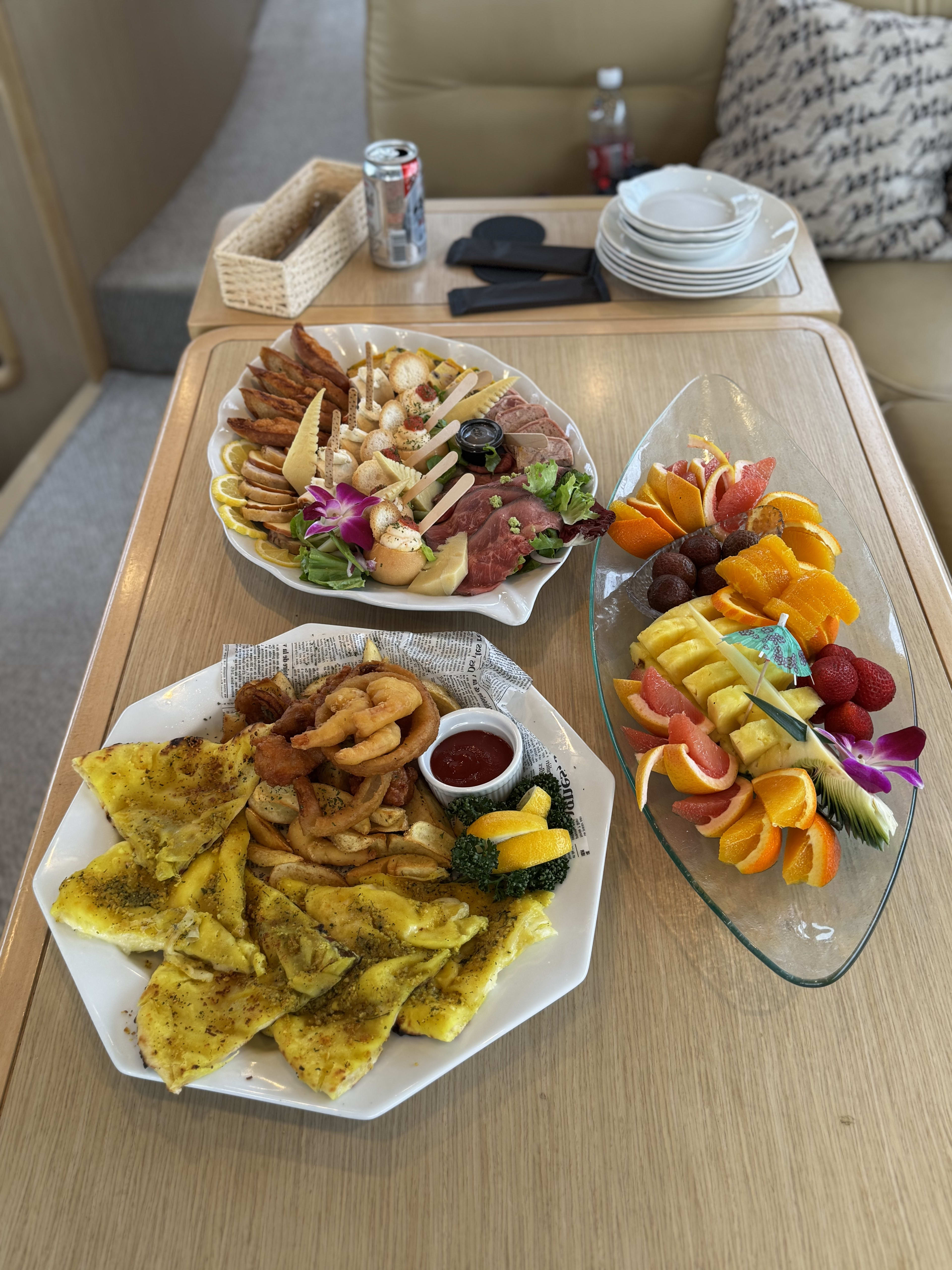 Charcuterie board, fruit platter and flatbread with onion rings on the yacht's table