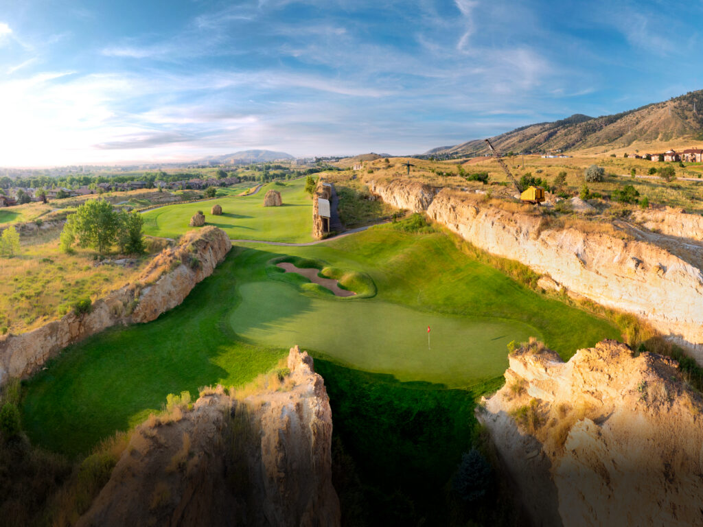 Spectacular aerial view of a dramatic golf hole carved through rugged canyon terrain with natural rock formations and a pristine green.
