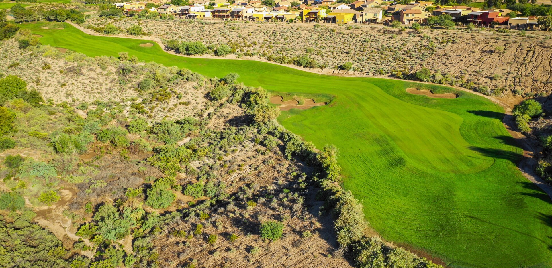 Stunning aerial view of Quarry Pines golf course showing dramatic elevation changes with lush green fairways winding through desert terrain and residential homes visible in background.