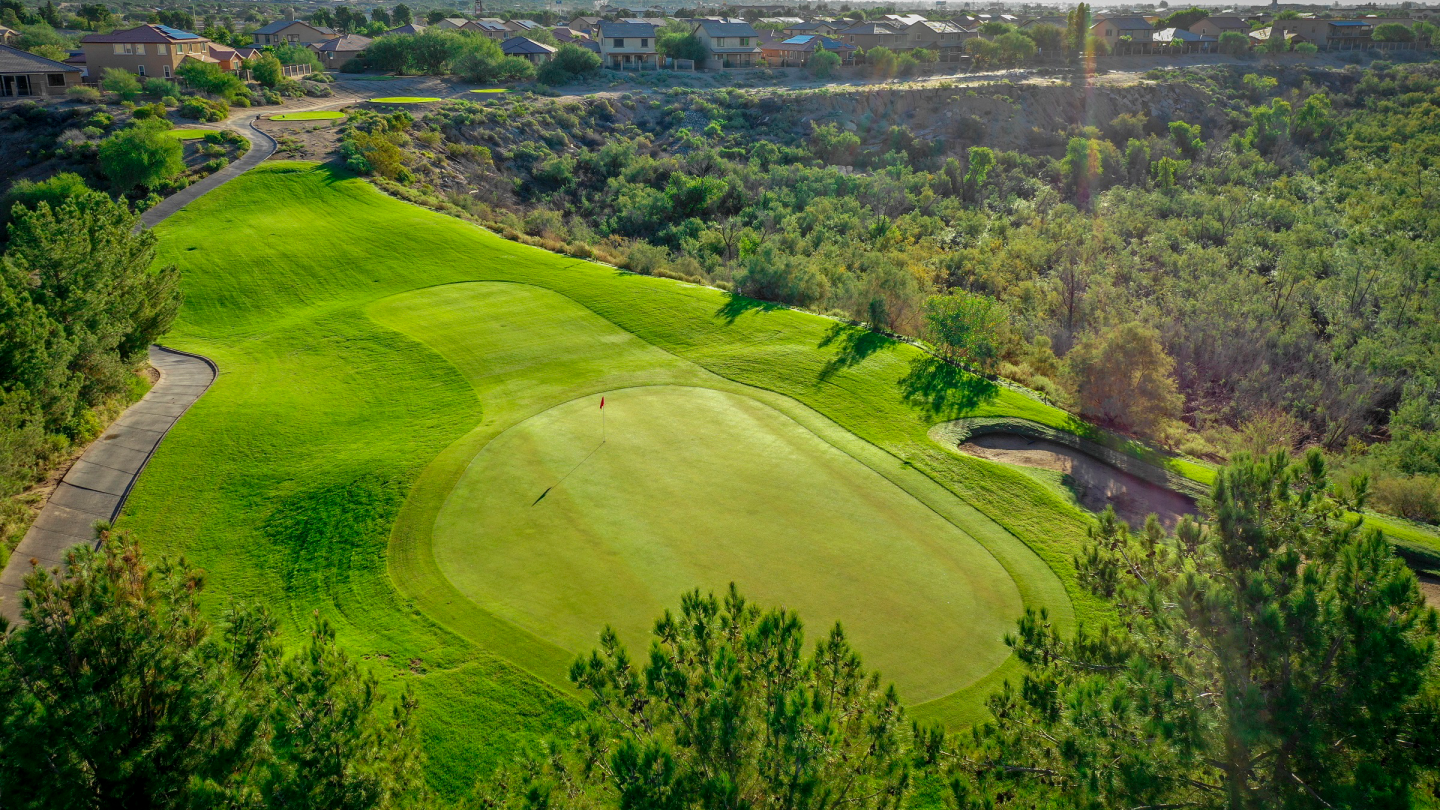 Spectacular aerial photograph of Quarry Pines golf course showcasing a pristine green surrounded by undulating fairways, cart paths, and natural desert landscape with residential development visible.