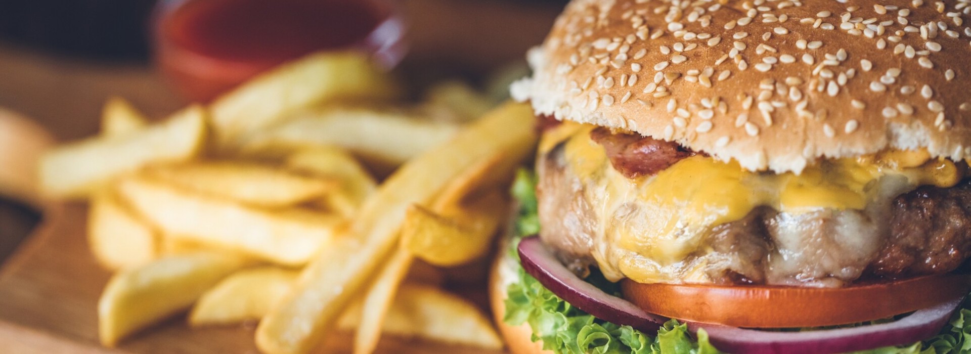 Close-up food photography showing a gourmet burger with melted cheese and bacon alongside golden french fries, representing the Putters Grill dining offerings.