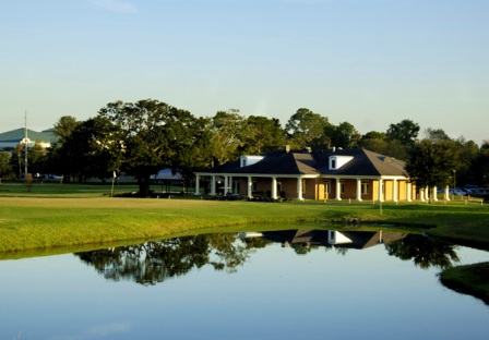 Elegant clubhouse with traditional architecture reflected in a water hazard during twilight hours.