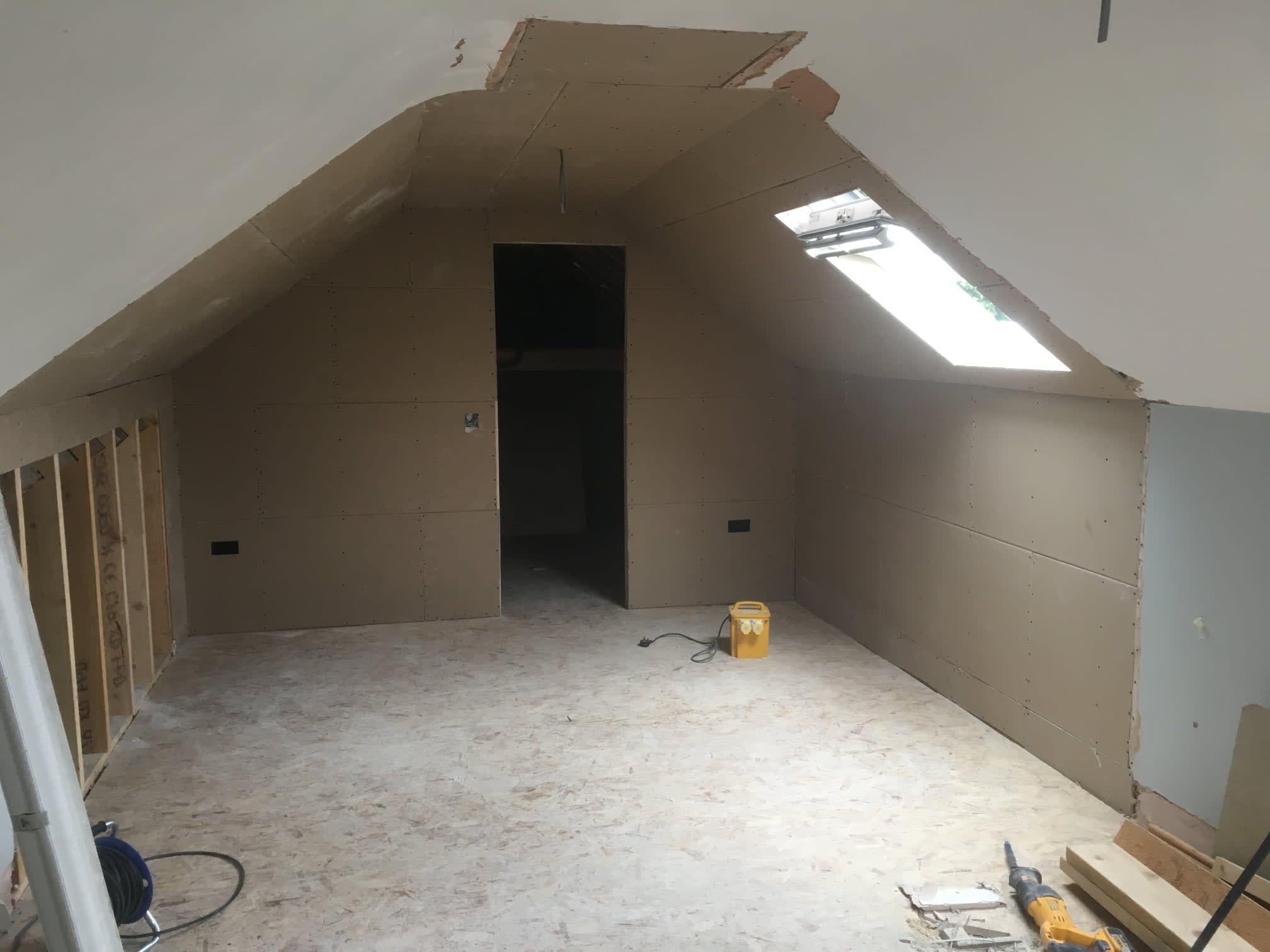  An image of an attic space being converted with plastic and wood showing on the walls 