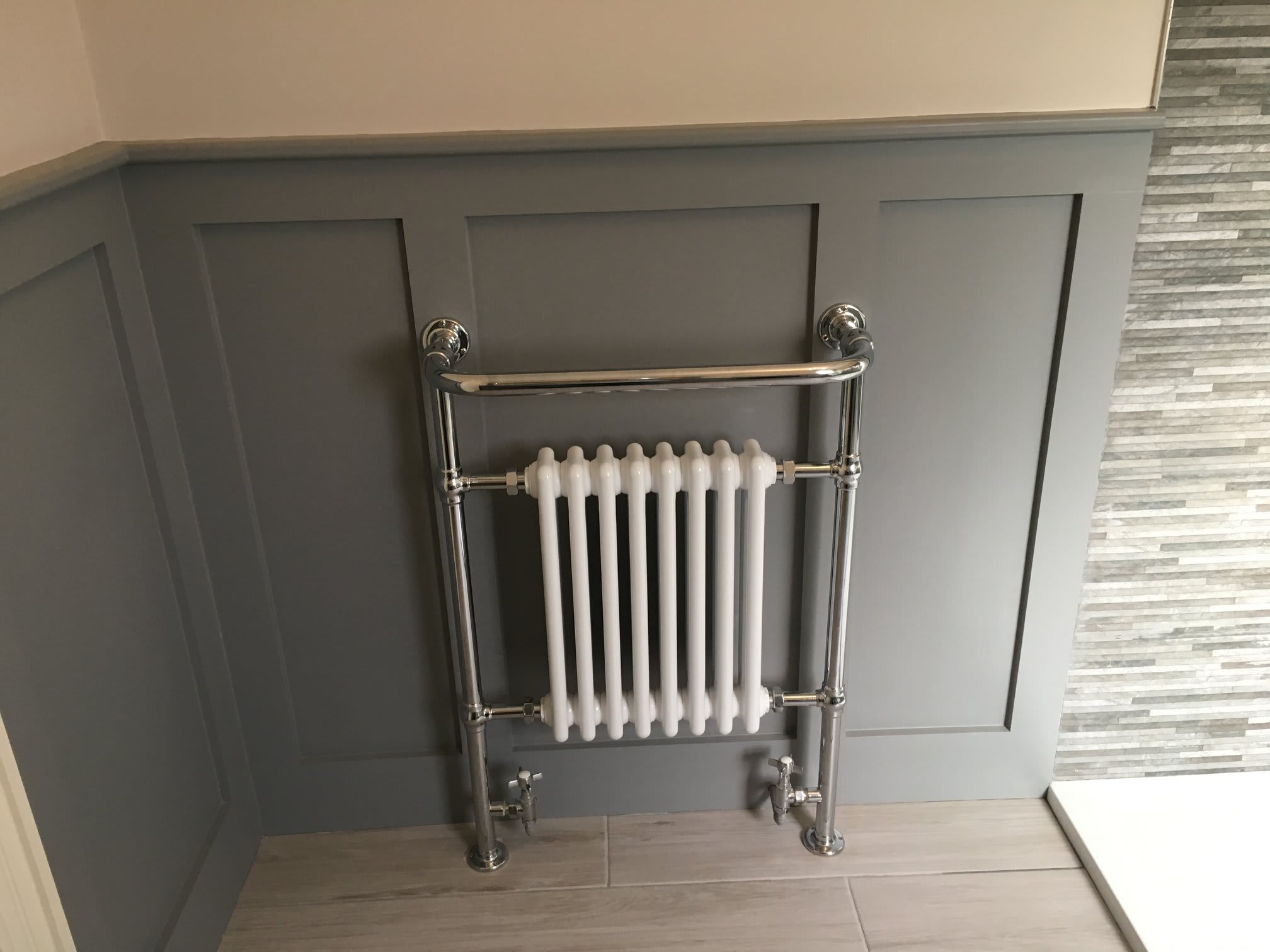 image of radiator installed on a wood panel wall in a bathroom