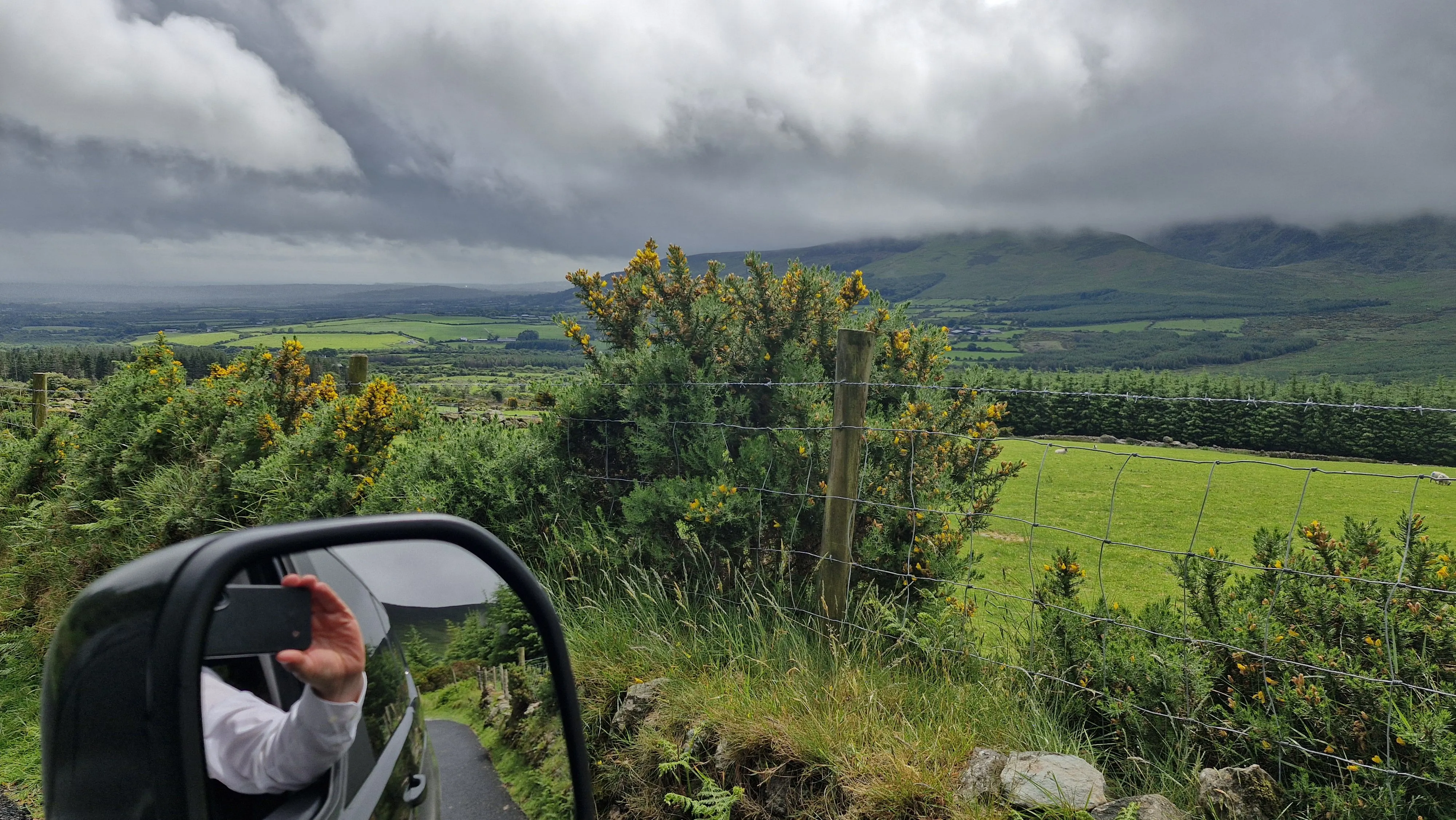 driving tour guide taking a photo from a car window of the irish countryside