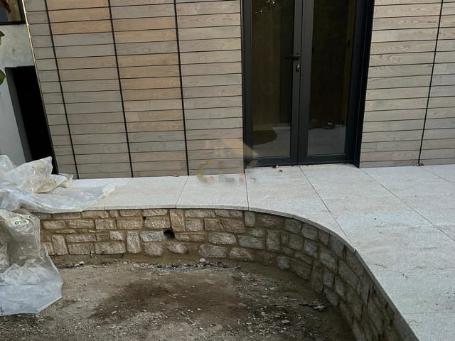 Muret courbe en pierre bordant une terrasse dallée